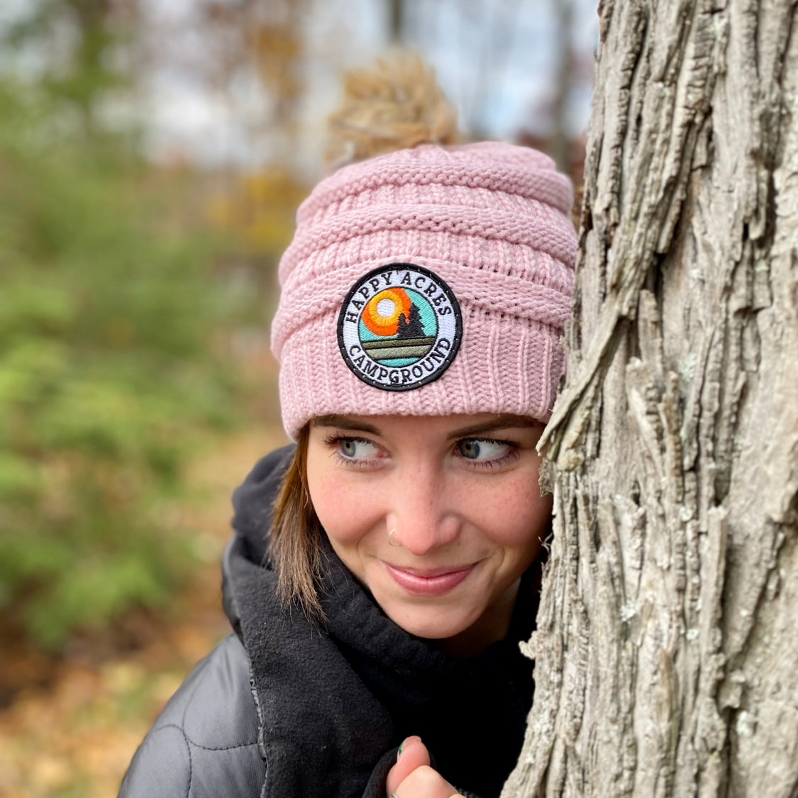woman wearing patch hat leaning on a tree