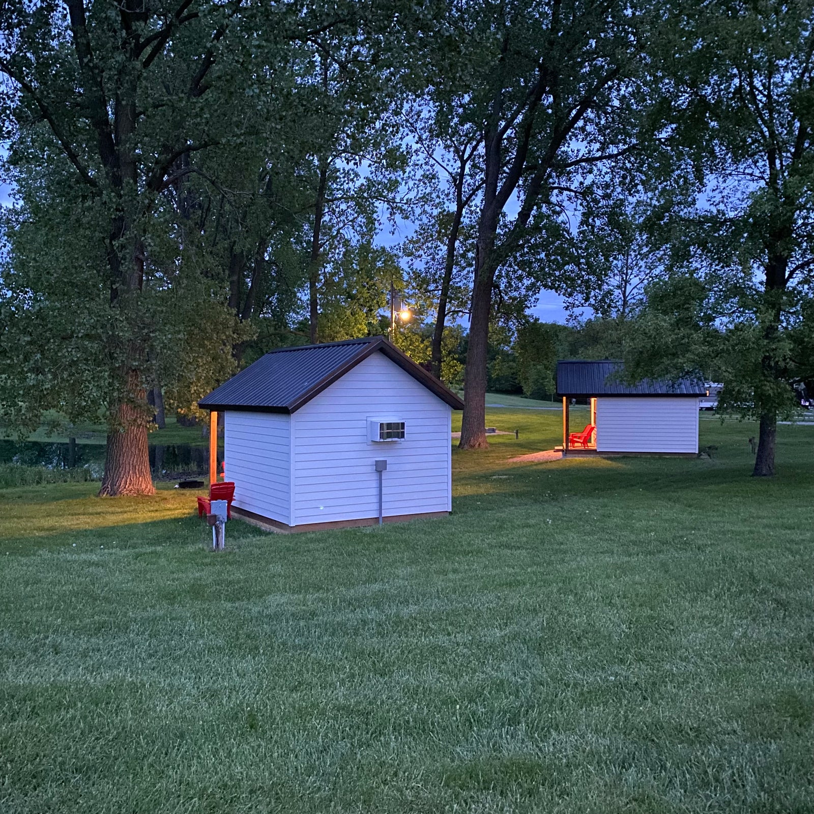 view of 2 cabins from behind with pond in the background