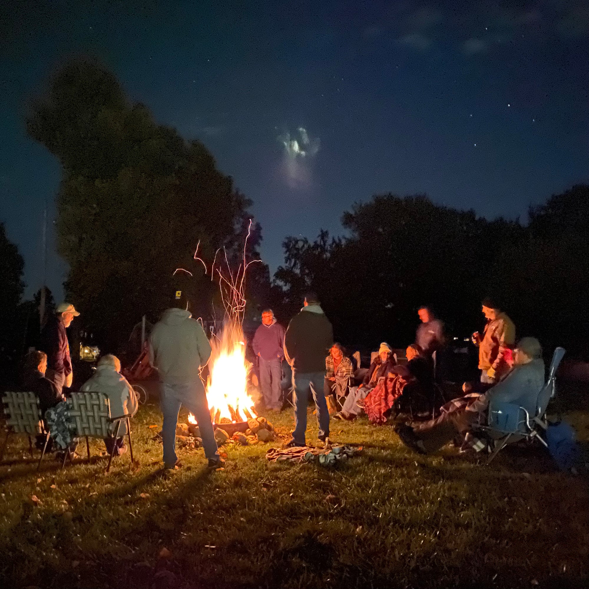 a group of friends gathered around a campfire in the dark
