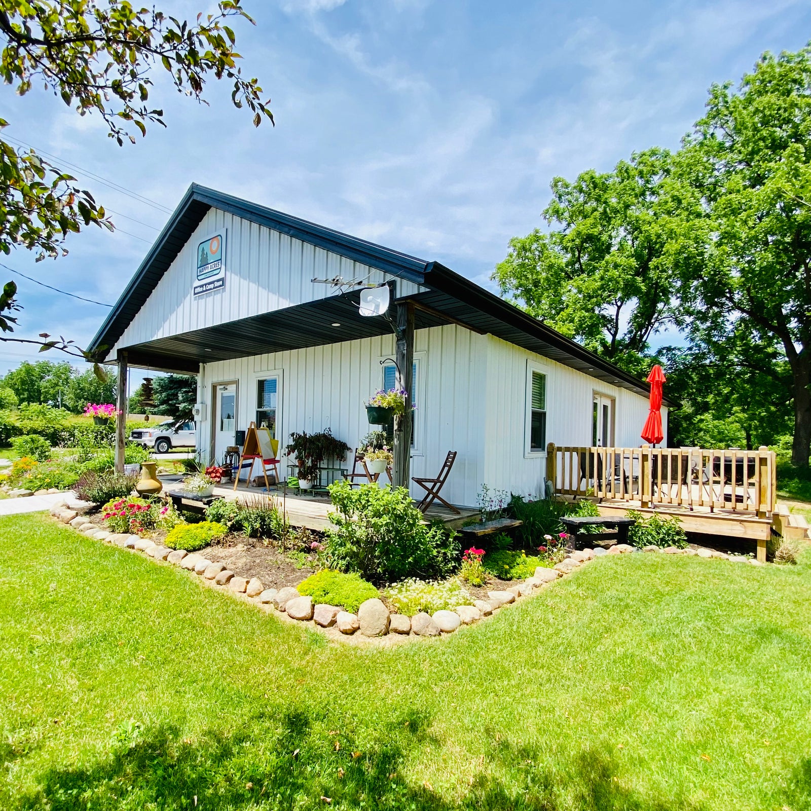 corner outside view of the camp store with flower garden and deck 