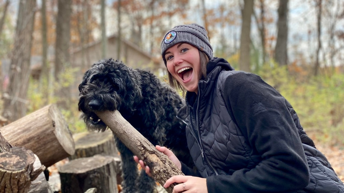woman playing with with dog and stick in the woods