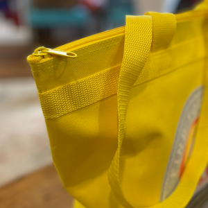 tote bag yellow with happy acres logo on the front up close of zipper